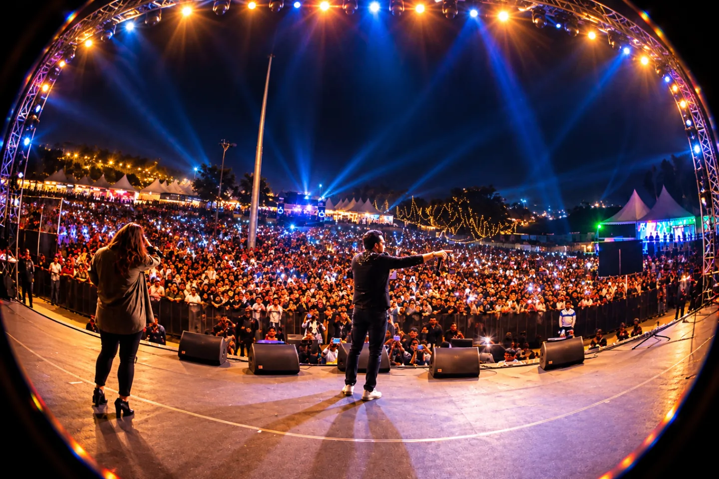 Live performers on an illuminated concert stage facing the crowd at an event organised by The Kabir Company