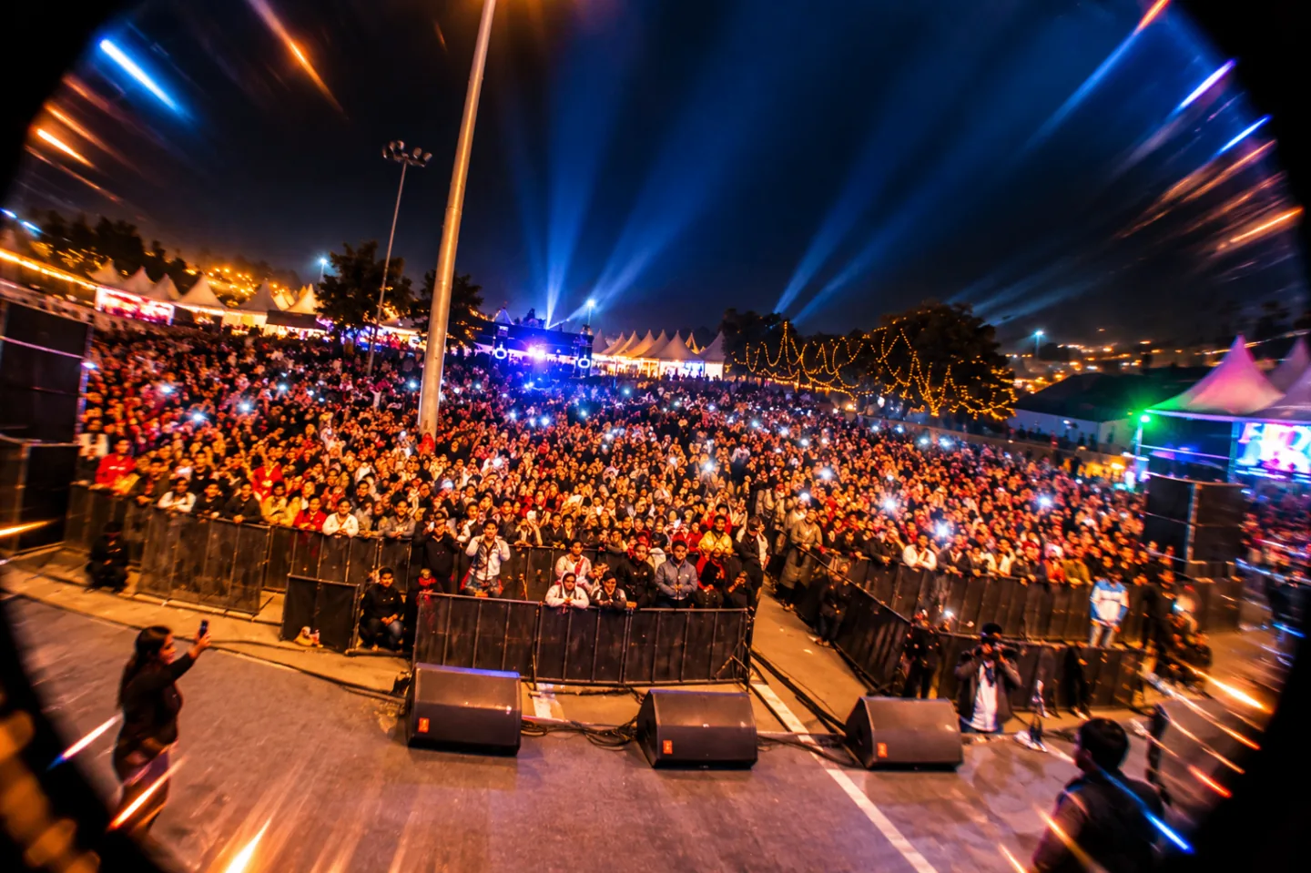 Open-air concert crowd with blue stage lighting at a The Kabir Company event